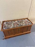 Front view of cedar blanket chest with floral tapestry cushion on top