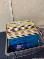 Side view of multiple vintage country vinyl records stacked in a plastic crate