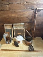 Full lot arranged showing metal scoop, two vintage washboards, enamel kettle, coal iron, coal scuttle, and wooden handled farm tool.