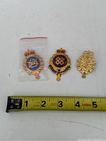 Three military money clips showing different Canadian Army regimental badges on a white background with measuring tape showing approx. 2 inches long.
