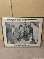Framed black and white poster showing The Rolling Stones band members with text praising Framus guitars by Bill Wyman