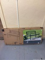 Photo of unopened packaged Hometrends outdoor bench with label and dimensions 50 x 21 x 33 inches.