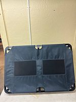 Full top-down view of the elevated pet bed showing the black fabric with two mesh ventilation panels and frame corners.