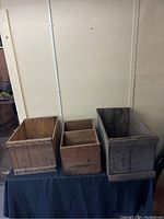 Three wooden crates placed side by side on a flat surface against a beige wall.