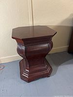 Full view of the dark wood plant stand showing its octagonal shape and curved sides with decorative carving.