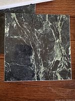 Black and white marbled tile with veining detail, approximately 12 by 12 inches