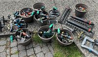 Wide view of assorted garden hose attachments, connectors, sprinklers, and spray guns placed on ground and in pots.