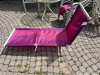 Purple portable lounge chair set up outdoors on paved surface