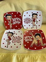 Four Betty Boop collectible porcelain dishes arranged in two rows, showing full designs and logos