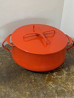 Red Dansk Kobenstyle casserole with lid, shown from top and side angle revealing shape, handles, lid handle.
