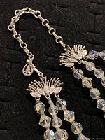 Close-up photo of the silver-toned bird motif clasp and faceted crystal beads of the 3 strand necklace.
