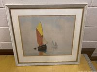 Front view of framed vintage sailboat print showing colorful sails and calm water scene.