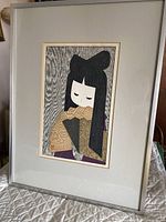 Full view of framed print leaning against table with quilted cover.