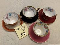 Top view showing 4 different vintage porcelain cups and saucers arranged with a note indicating 5 pieces but only 4 sets