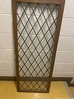 Full view of the vintage leaded glass window with cross hatch lattice in wooden frame.