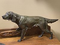 Side view of the bronze-colored cast metal Irish Setter dog statue showing detailed fur texture and pointing stance.