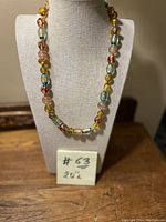 Full view of the colorful Murano glass bead necklace displayed on a beige fabric bust with note indicating 20 inch length.