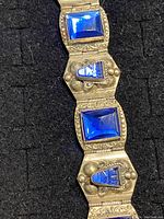 Close-up photo of rectangular and trapezoid blue stones set in carved silver with detailed beadwork and floral designs.