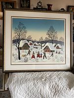 Full view of framed vintage winter village scene print showing a snowy village with people and houses.