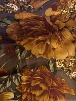 Close-up of yellow floral pattern on dark brown silk scarf showing material texture and colors.