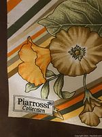 Close-up of scarf corner with Piarrossi Collection label and part of floral design with striped background.