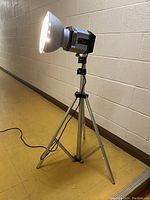 Full side view of the vintage Cameron Quartz-Imager studio lamp mounted on the aluminum tripod, lamp is off but connected to power cord.