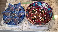 Photo showing the entire set with the star-shaped platter on the left and large round bowl on the right, both decorated with colorful intricate patterns.