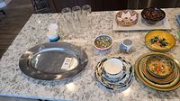 Photo showing all items together on a marble countertop including dishes, metal platter and glass jars.