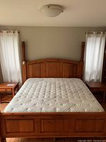 Front view of assembled pine bed frame with mattress and side tables