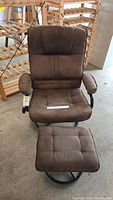 Front view of brown plush fabric recliner with attached cushioned armrests and matching ottoman on black swivel base.
