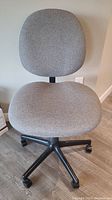 Front view of Steno gray fabric office chair showing the curved backrest and contoured seat on a black five-star caster base.