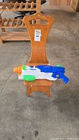 Wooden long handled step stool with the Nerf water toy placed on the seat, visible wear on the stool and color details on the water toy