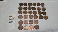 Group layout of approximately 40 British One Penny coins from 1928-1967, arranged in rows on a white cloth.