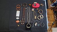 Photo of assorted vintage Bakelite bangles, costume jewelry bracelets, necklaces, brooches, and rings laid out on dark fabric.