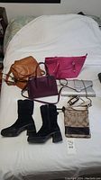 All handbags and boots in group on bed for overview
