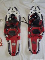 Pair of GV Trail Series 8x25 Cat Trail snowshoes lying on fabric, showing full top view with red binding straps and metal frames.