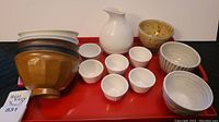 Full shot of the set on the red tray showing the sake pitcher, sake cups, and assorted pottery bowls
