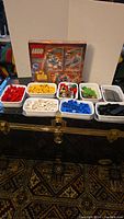 Photo showing the sealed LEGO Alien Discovery Mars box and nine white plastic containers filled with LEGO bricks organized by color.
