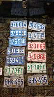 Top view showing 12 vintage British Columbia license plates in different colors and years, displayed on a patterned carpet.