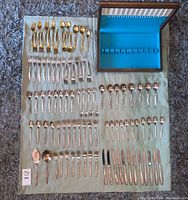 Full layout of the mixed silverware pieces including gold and silver toned forks, spoons, knives, plus silverware storage box