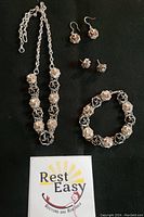 Full set of sterling silver rose jewelry with necklace, bracelet, ring, and earrings on black background