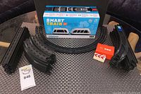Boxed Intelino Smart Train with curved and straight track pieces and accessories laid out on a woven mat surface