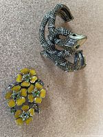 Photo showing Carolee snake cuff bracelet and vintage floral brooch with yellow enamel flowers and green rhinestones, one small rhinestone missing on the brooch.