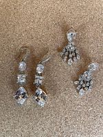Photo of two pairs of earrings on a neutral corkboard background, showing crystal drop earrings and Carolee mini chandelier earrings in excellent condition