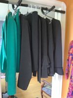 Multiple blazers hanging on a rack including a green blazer and several black blazers, showing structure and style variety
