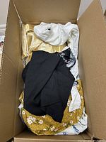 Box with mixed women's clothing in XL and 1XL sizes showing various fabrics and colors including black, white, gold, and floral prints.