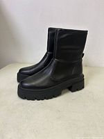 Side view of black boots showing mid-calf height and lug sole.