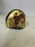 Front view of curved stone with Byzantine icon of St. George in armor on white horse with red cape, gold gilded background.