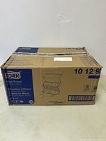 Tork cardboard box containing paper towels with hand towel illustration and brand name visible.