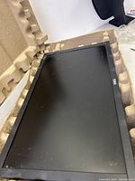 Dell E2020H 20-inch widescreen LED monitor with black bezel shown lying inside molded packaging material.